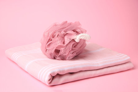 Shower puff with towel on pink background
