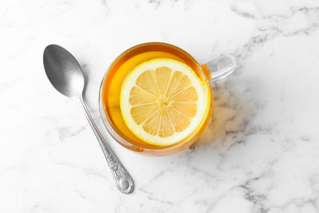 Aromatic tea with lemon in cup and spoon on white marble table, top viewの写真素材