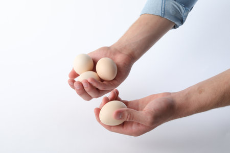 Man with raw chicken eggs on white background, closeupの写真素材