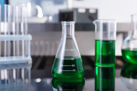 Glass flask and other glassware with green liquid on table in laboratory, closeupの写真素材