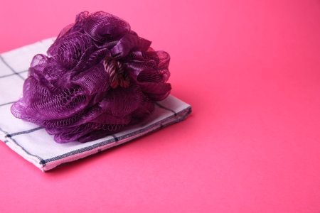 Purple shower puff and towel on pink background, space for text