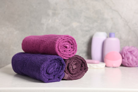 Fresh rolled towels and cosmetic products on white table, closeupの写真素材