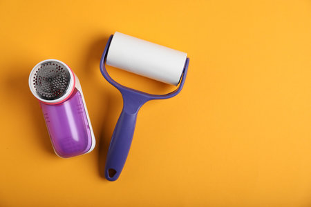 Lint roller and fabric shaver on orange background, flat lay. Space for textの写真素材