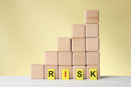 Word Risk and stacked cubes on white wooden table against beige backgroundの写真素材