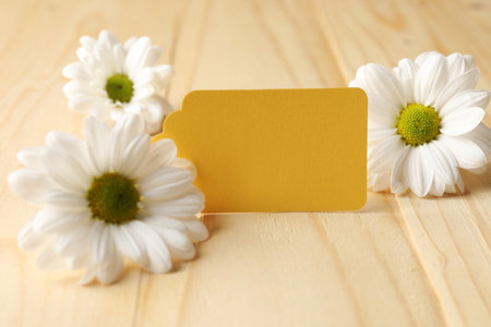 Blank tag and flowers on wooden table, closeupの写真素材