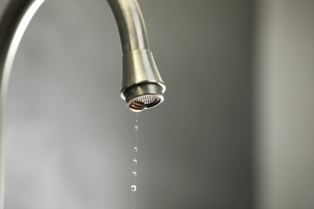 Water saving concept. Water dripping from tap against gray background, closeup. Space for textの写真素材