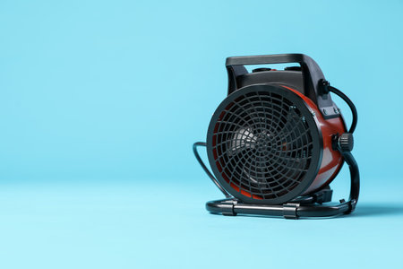 Electric fan heater on light blue background. Space for textの写真素材