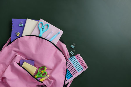 Happy teacher's day. Backpack with stationery on green background, flat lay. Space for textの写真素材