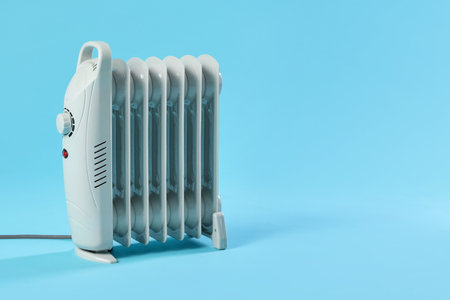 Electric heater on light blue background. Space for textの写真素材