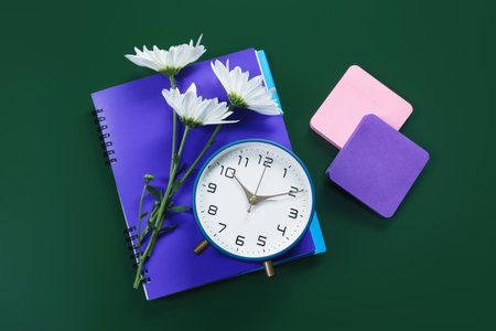Notebook, alarm clock, flowers and sticky notes on green background, flat layの写真素材