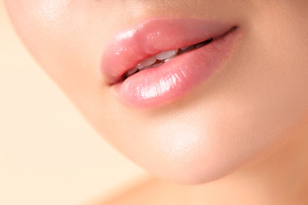 Woman with beautiful lips on beige background, macro viewの写真素材