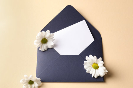Blank card, envelope and flowers on beige background, flat layの写真素材
