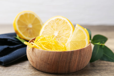 Lemon zest, fresh fruits and green leaves on wooden table, closeup