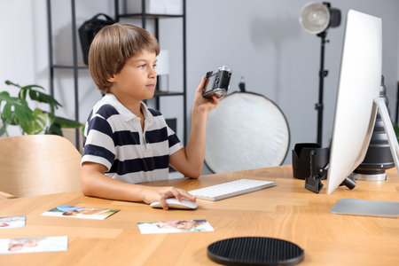 Choice of profession. Little boy with camera pretending to be photographer at wooden table in studio