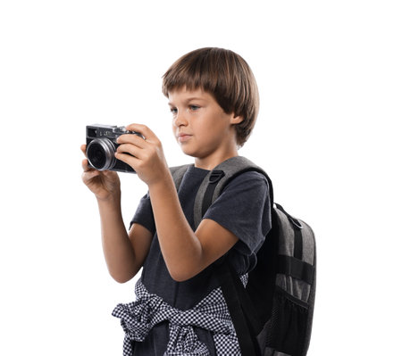 Choice of profession. Little boy with camera and backpack pretending to be a photographer on white...