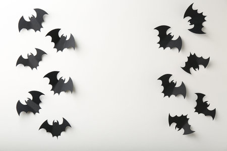 Halloween decor. Black paper bats on white background, flat lay. Space for text