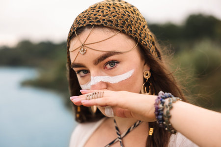 Beautiful shaman woman with face painting and jewelry outdoors, closeup. Space for text