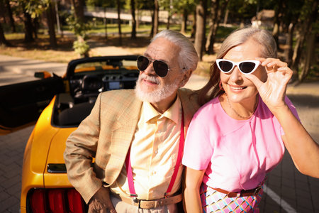 Stylish senior couple in sunglasses near modern cabriolet outdoorsの写真素材