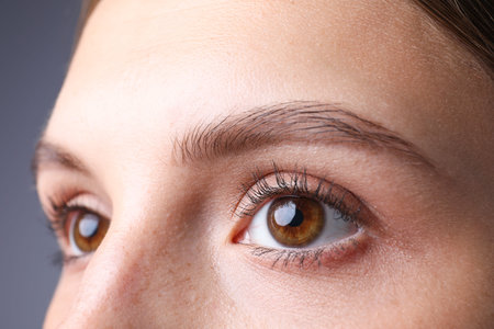 Woman with beautiful eyes on gray background, closeup