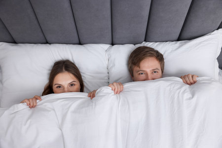 Lovely couple lying in bed at home, top viewの写真素材