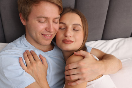 Lovely couple enjoying each other in bed at home, above viewの写真素材