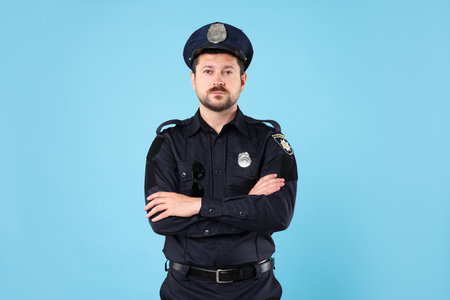Policeman in uniform posing on light blue backgroundの写真素材
