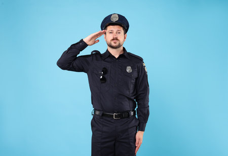 Policeman in uniform posing on light blue backgroundの写真素材