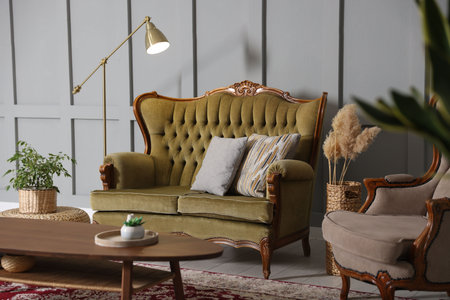 Soft sofa, table, armchair and lamp near gray wall in living room. Interior design