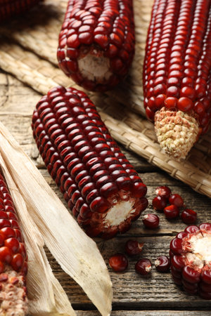 Ripe red corn cobs on wooden table, closeup