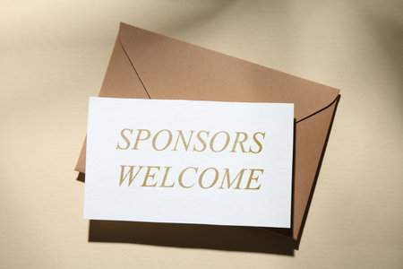 Paper with phrase Sponsors Welcome and envelope on dark beige background, top viewの写真素材