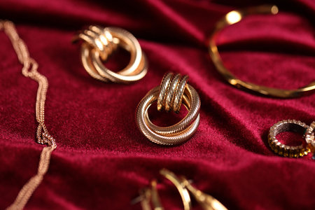 Stylish gold jewelry on red cloth, closeupの写真素材