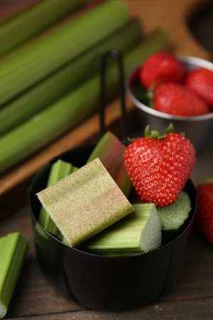Cut fresh rhubarb and strawberries on wooden table, closeupの写真素材
