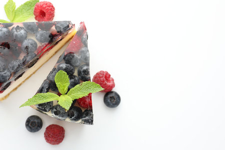 Pieces of delicious cheesecake with berries and mint on white table, flat lay. Space for textの写真素材
