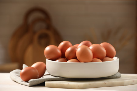 Raw chicken eggs and bowl on white table in kitchen. Space for textの写真素材