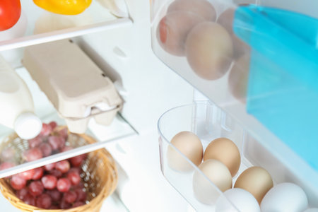 Raw chicken eggs and other food products in refrigerator, closeupの写真素材