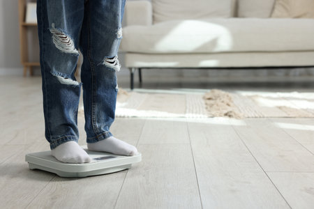Little boy measuring his weight on scales at home, closeup. Space for textの写真素材