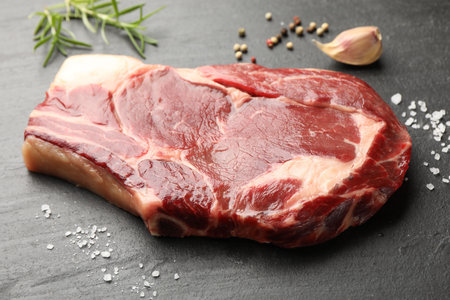 Piece of raw beef meat and spices on black table, closeupの写真素材