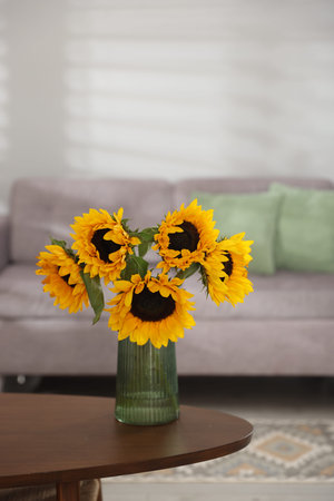 Beautiful sunflowers in vase on wooden table indoorsの写真素材