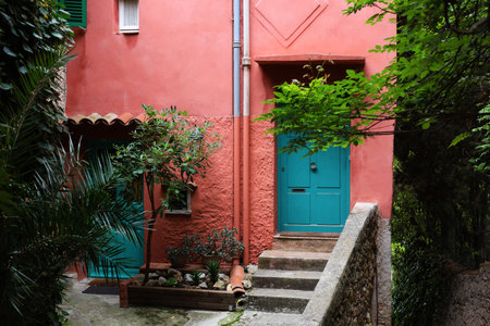 Beautiful red building with green door and different plants outdoorsの写真素材