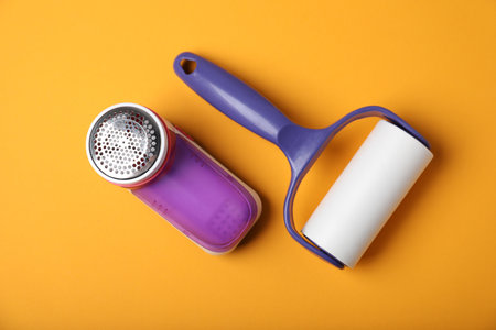Lint roller and fabric shaver on orange background, flat layの写真素材
