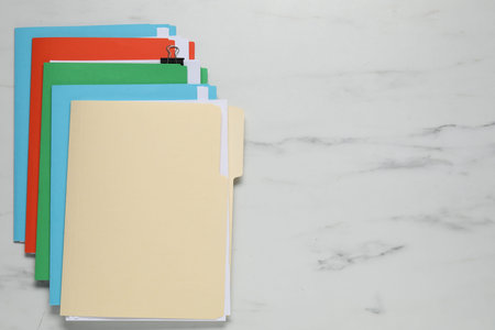 Many documents in folders with binder clip on white marble table, top view. Space for text