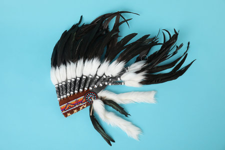Traditional warbonnet (Native American chief headdress) on light blue background, top view