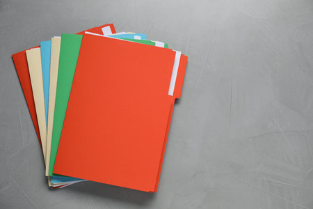 Many documents in folders on gray table, top view. Space for text