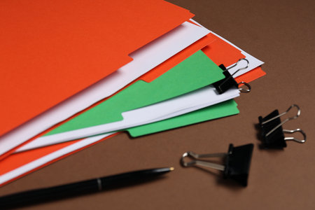 Many documents in folders with binder clips and pen on brown background, closeupの写真素材