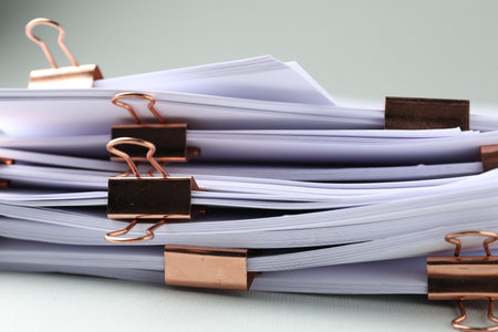 Many documents with binder clips on light gray background, closeupの写真素材