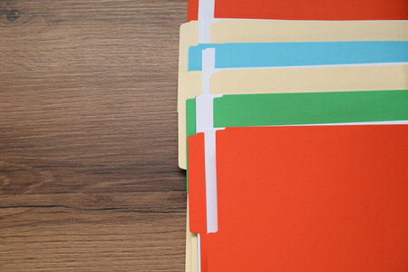 Many documents in folders on wooden table, top view. Space for text