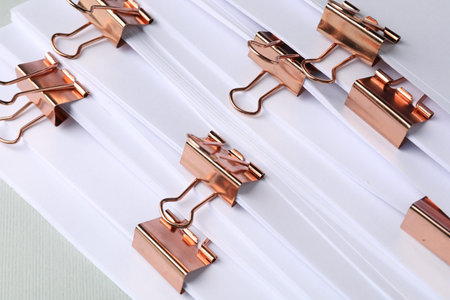 Many documents with binder clips on light background, closeup