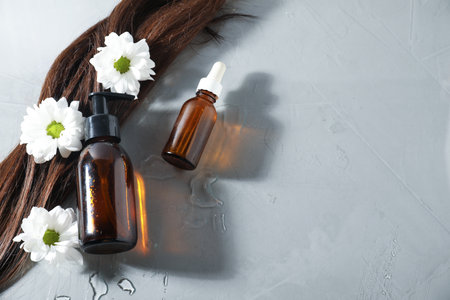 Hair lock, cosmetic products and flowers on light background, above view. Space for textの写真素材