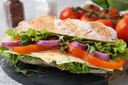 Delicious sandwich with prosciutto, cheese and vegetables on light table, closeupの写真素材