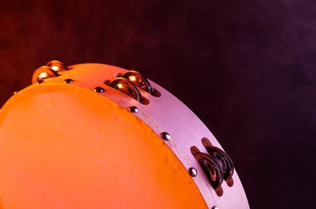 Tambourine in color light on dark background with smoke, closeupの写真素材